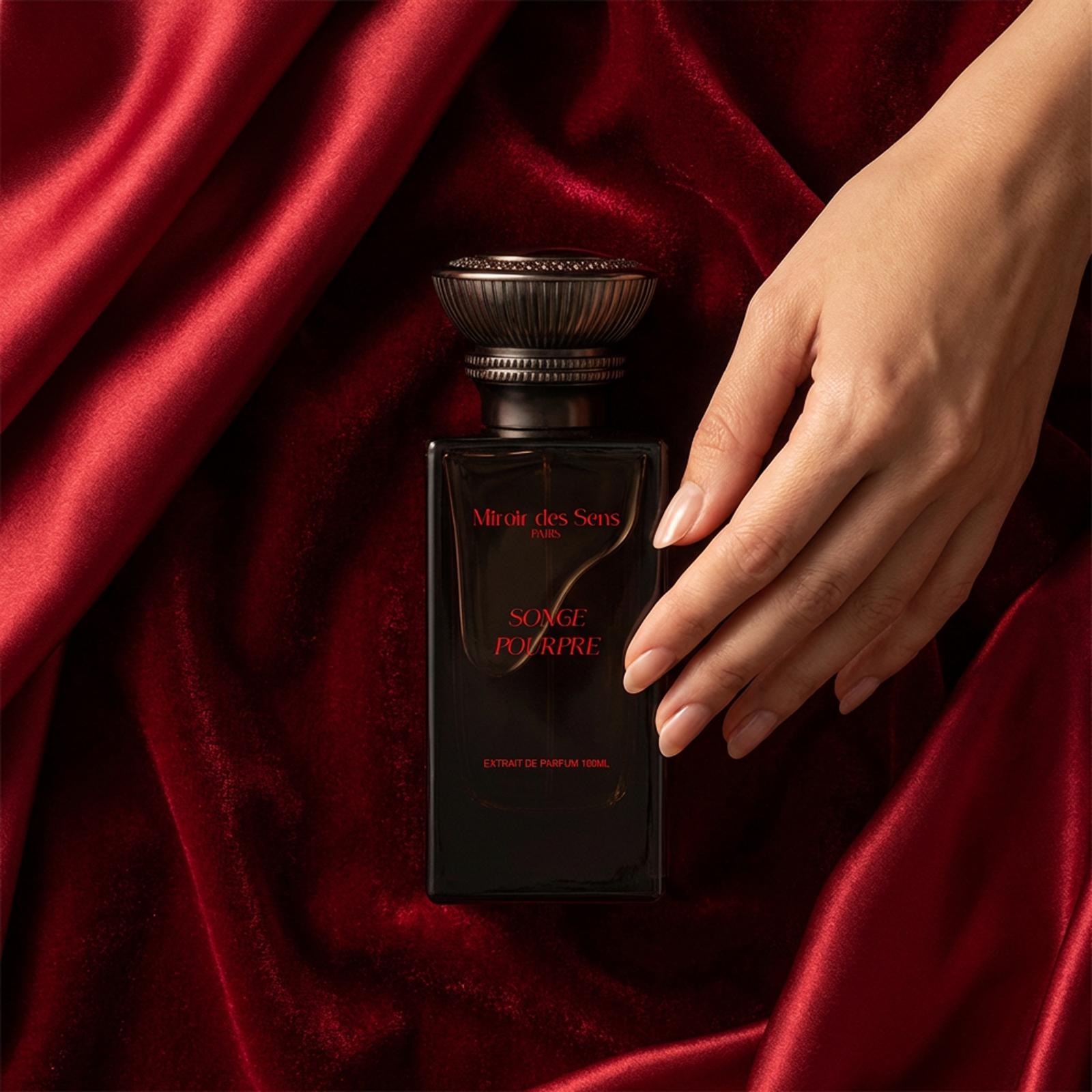Flacon Miroir des Sens Songe Pourpre posé sur un velours rouge profond