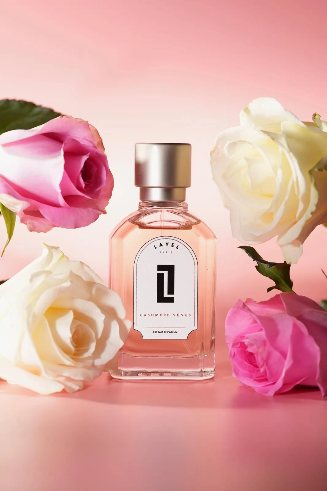 Cashmere Venus, LAYEL PARIS — flacon posé au centre d'une couronne de roses pâles et fuchsia