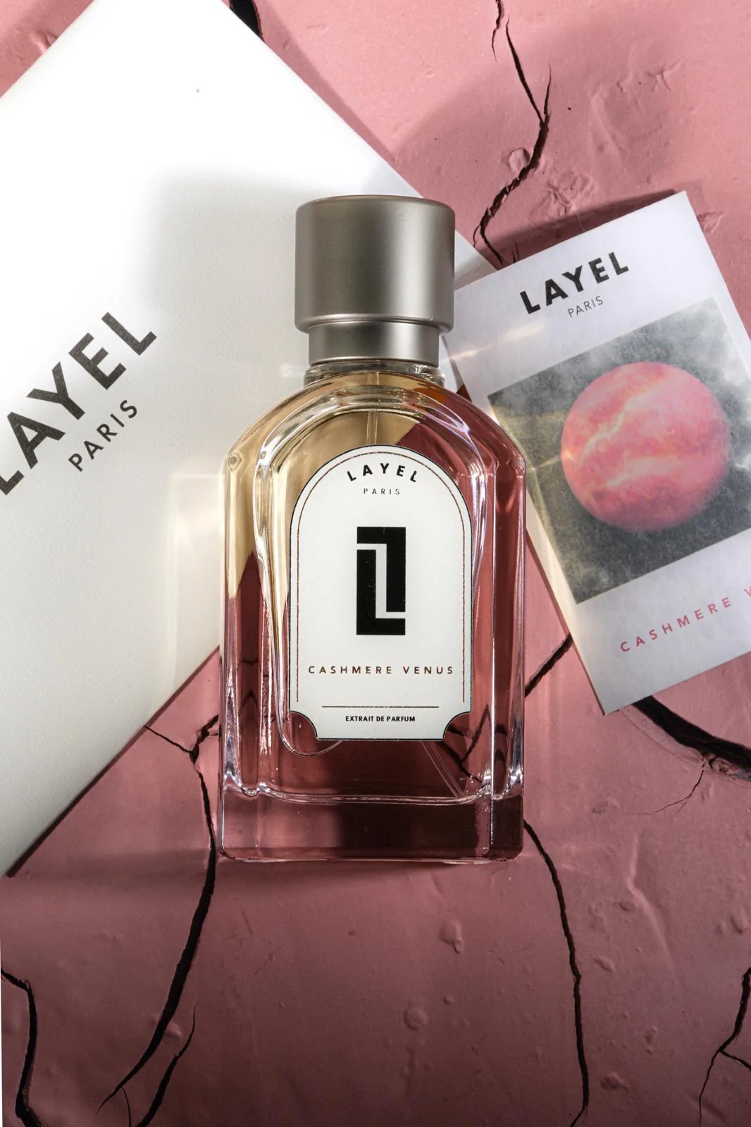 Cashmere Venus, LAYEL PARIS — mise à plat du flacon et de son coffret sur plâtre rose craquelé